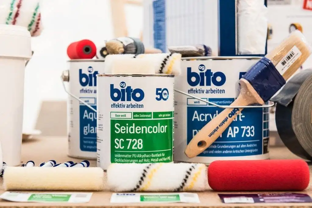 Das Foto zeigt ein Sortiment von Produkten der Marke bito auf einer Arbeitsfläche. Im Zentrum stehen mehrere Dosen und Behälter mit dem bito-Logo (blau-weiß) und dem Schriftzug „effektiv arbeiten